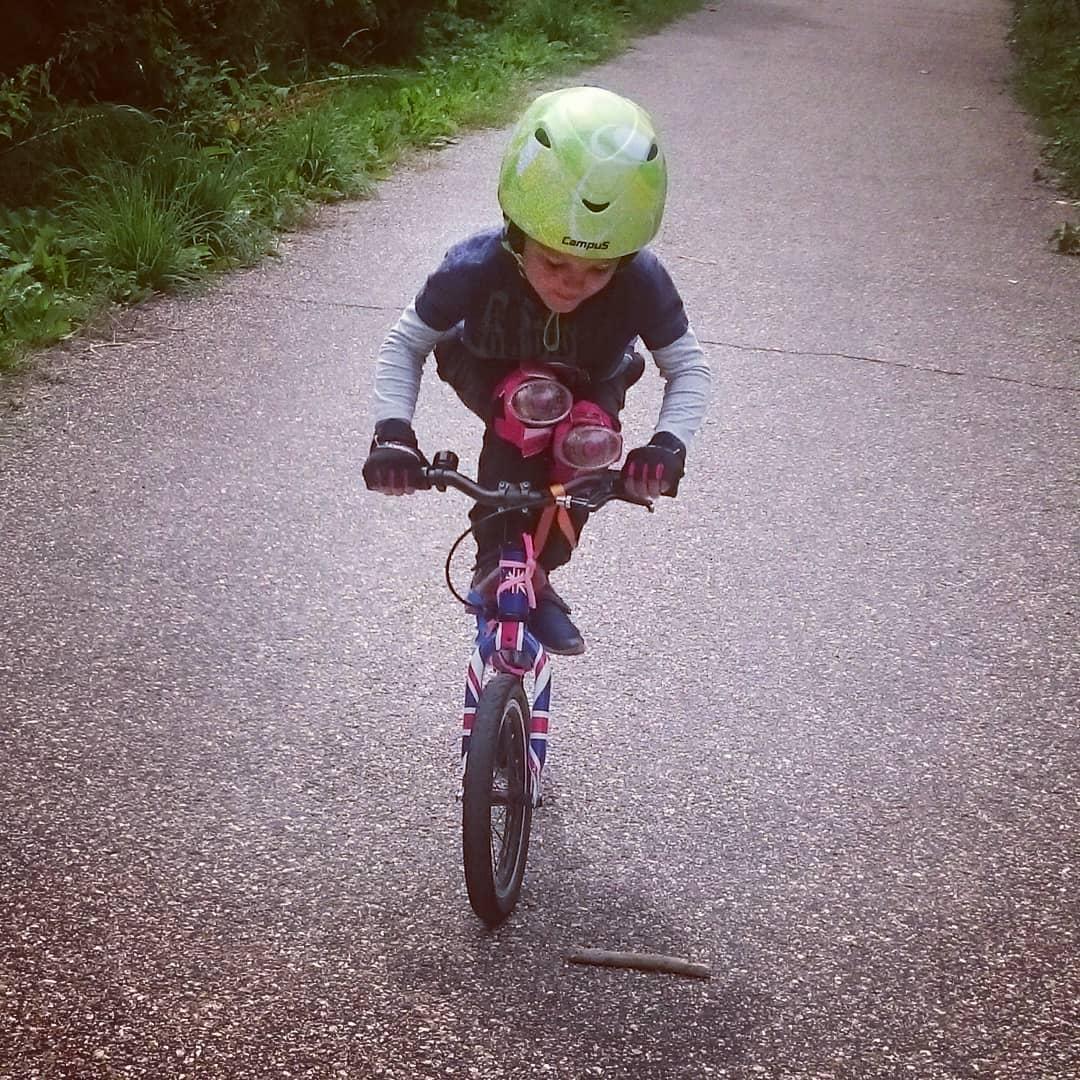 small boy standing on the top tube of his balance bike practicing bike skills taken by instagram @ habwright
